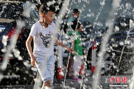 山西太原最高溫36℃,兒童在噴泉周圍戲水消暑。