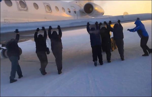 伊加爾市一架客機起飛前被凍在了跑道上。飛機上的乘客不得不下來推飛機。