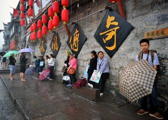 　4月29日上午11時(shí)20分，一些游客和古城當(dāng)?shù)氐木用穸阍谝粋€(gè)酒吧的屋檐下避雨。這些當(dāng)?shù)鼐用褚詾橛慰团恼罩\生，一場(chǎng)降雨讓他們的生意更加清淡。