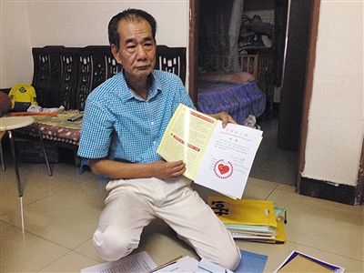 翻出一家網(wǎng)站贈予的“中國好人”證書，區(qū)少坤單膝跪在地上，“你看，我是中國好人啊?！?范春旭 攝