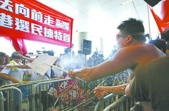 17日，在香港立法會(huì)外，一名反對(duì)政改的男子向支持派人群投擲標(biāo)牌。