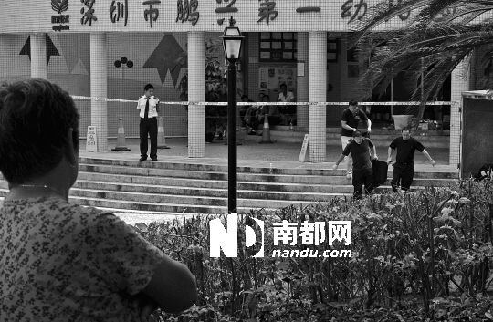 →7月19日，鵬興花園第一幼兒園門前，民警在現(xiàn)場進(jìn)行完勘查取證后，園長和保安的尸體被運(yùn)走。南都記者 徐文閣 攝