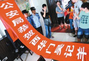 面對警方收繳的條幅，老板楊某也不好意思地用手遮擋臉