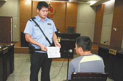 昨日庭審中，法警向趙某出示其扎完車胎后所留辱罵公司的紙條。通訊員 李秀文 攝