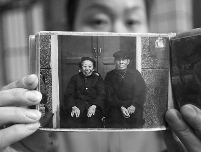 圖為孫女拿出兩位老人上世紀(jì)80年代在家門(mén)口的合影給記者看。記者楊濤 攝