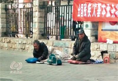 工人體育場北路，兩位乞討者路邊乞討，并輪流扮成“病人”（躺地者）。 央視截圖