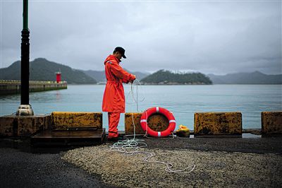 7月6日，韓國珍島，一名海岸警察在港口系救生圈。4月，客輪在珍島近海發(fā)生沉船事故后，仍有11人下落不明。