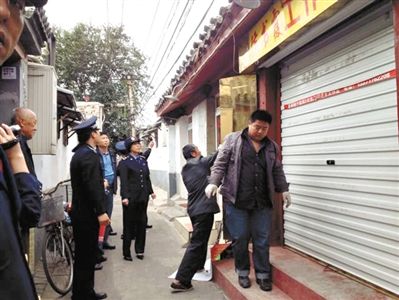 執(zhí)法人員拆除胡同里一家店面未經(jīng)審批的招牌。