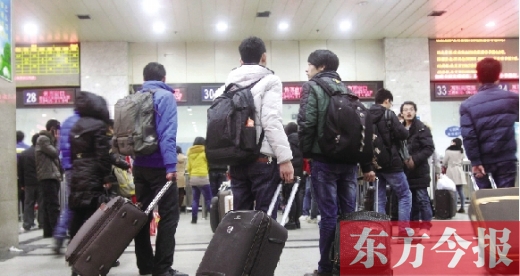 鄭州火車(chē)站東廣場(chǎng)售票大廳，幾名學(xué)生在售票窗口前躊躇