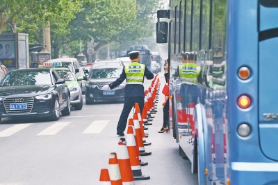 省人民醫(yī)院南門的路中間擺放反光錐，交警示意由西向東車輛從前方繞行。