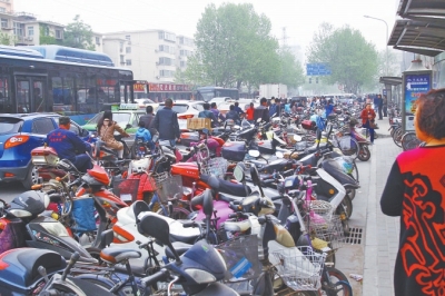 省人民醫(yī)院北門，路邊的公交站牌處停滿非機動車，上、下客只能在快車道上。
