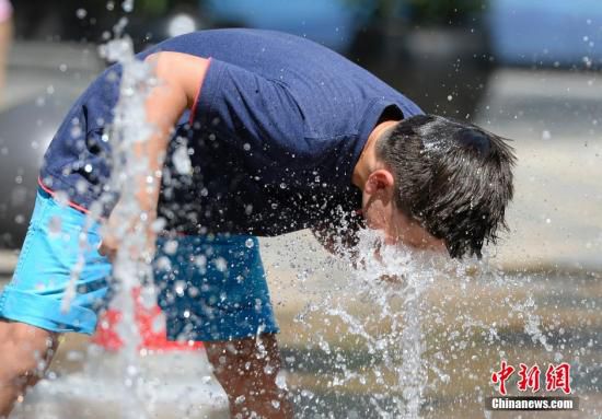 5月29日，一名小孩將頭伸向北京街頭的噴泉以降溫祛暑。