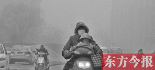 12月8日，鄭州市未來路上，一位市民帶著孩子在霧中騎行