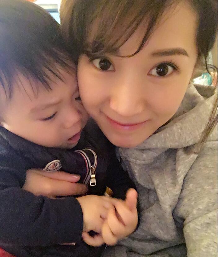 照片中李念狂吻兒子，小寶貝自顧自地玩著。
