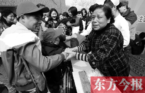 昨日，鄭大四附院的大樓前，“面人鄭”鄭玉芬（右）向前來捐款的殘疾人表示感謝