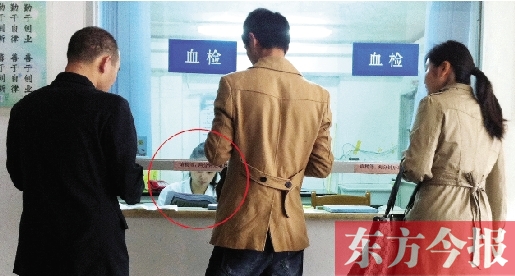 昨日，鄭州市二七區(qū)疾控中心辦證大廳，血檢窗口內(nèi)一名女工作人員，邊接受辦證者咨詢邊看報紙