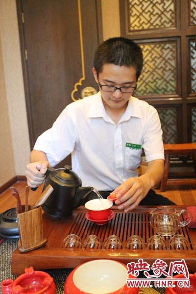 1、水壺里的水煮沸，李克勤把茶葉放進茶荷里，準備溫杯沖茶