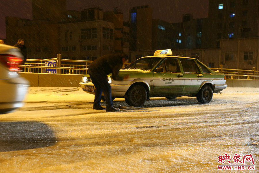 一位出租車司機(jī)在車輪前灑上雪，希望能增加輪胎的摩擦力。