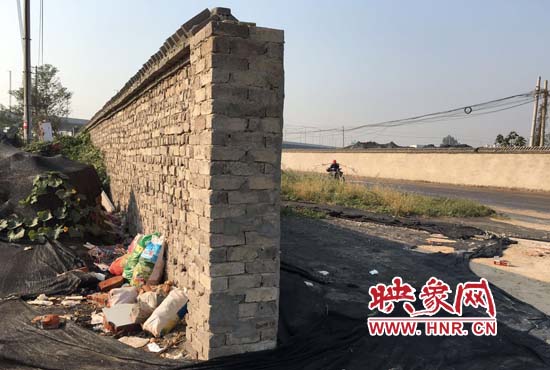 一墻之隔，一邊是道路，一邊是垃圾和荒草，市民質(zhì)疑其為遮羞墻。