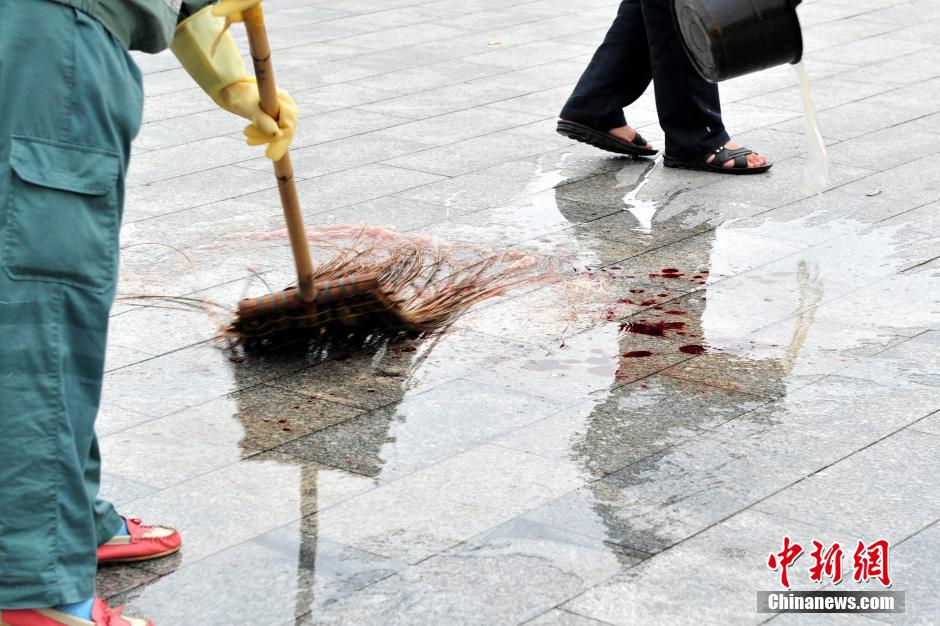圖為環(huán)衛(wèi)工人在清理案發(fā)地點的血跡。