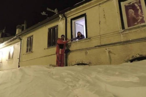 一個居民站在積雪上，可以與一名二樓鄰居在窗口握手。（來源：意大利氣象局）