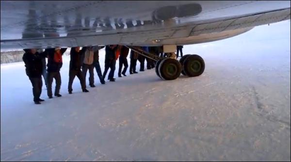 　伊加爾市一架客機起飛前被凍在了跑道上。飛機上的乘客不得不下來推飛機。