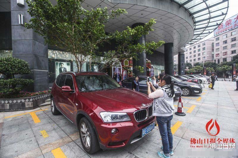一輛停在停車位上的寶馬轎車，被墜落的樹枝砸中，樹枝徑直插入車內(nèi)，現(xiàn)場(chǎng)引發(fā)不少市民圍觀拍照。