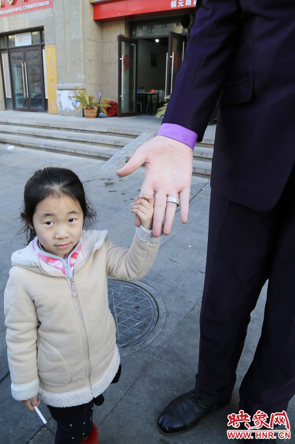 巨人“張歡”牽著一名漂亮的小女孩，兩人的手大小對比非常明顯。