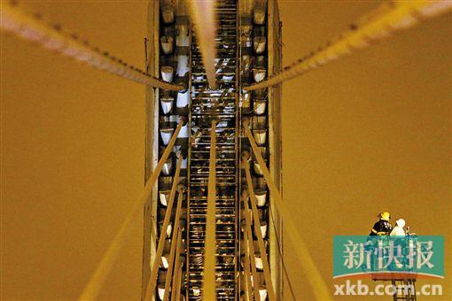 截至今日零時(shí)，男子仍未有下橋舉動(dòng)。圖為公安和消防人員乘消防云梯在高空上和男子交談。